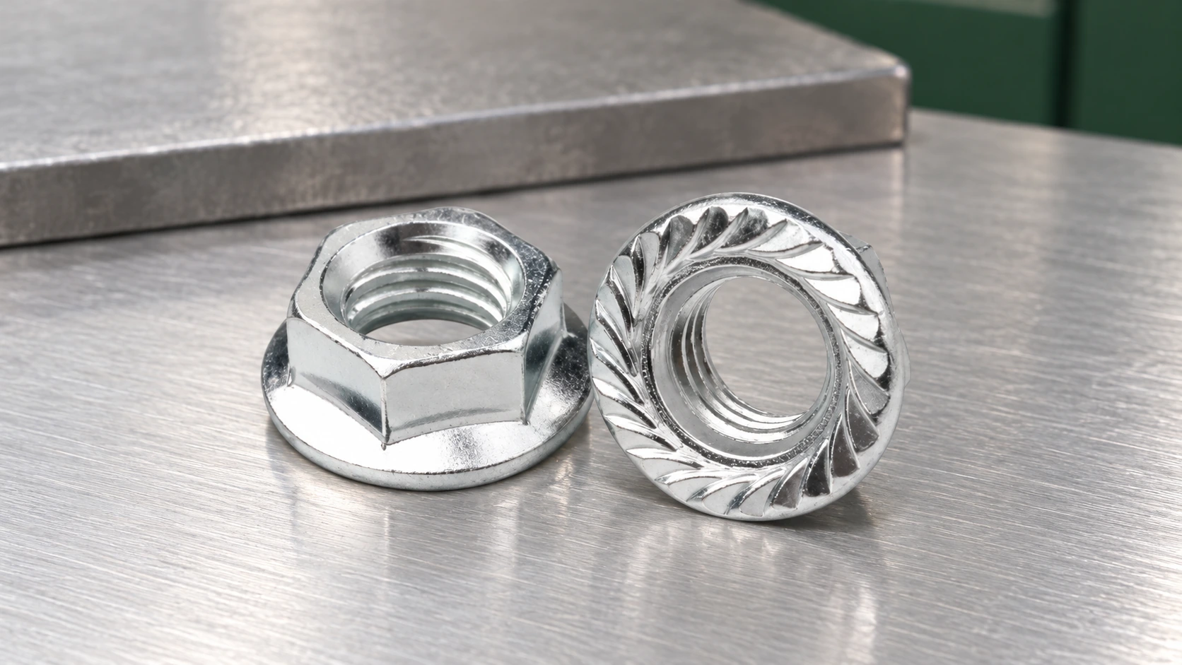 Two illustrative silver flange nuts on a steel bench, showing the hexagonal body and serrated bearing face.